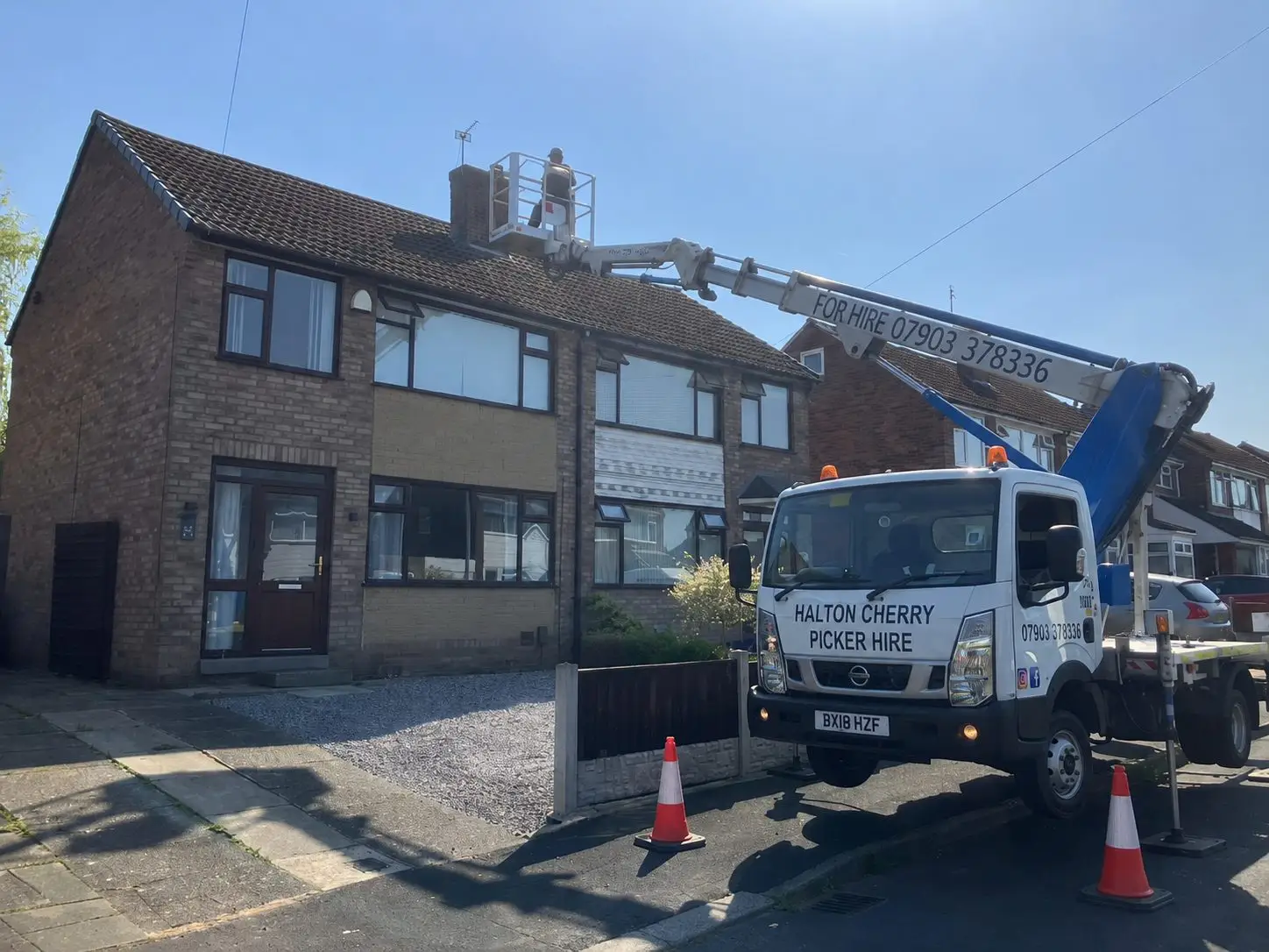 Halton Cherry Picker Hire vehicle with an operator in the basket working on a house roof